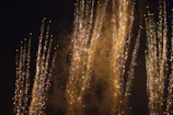 Close-up of sparkling fireworks shooting upwards with trails of golden sparks.