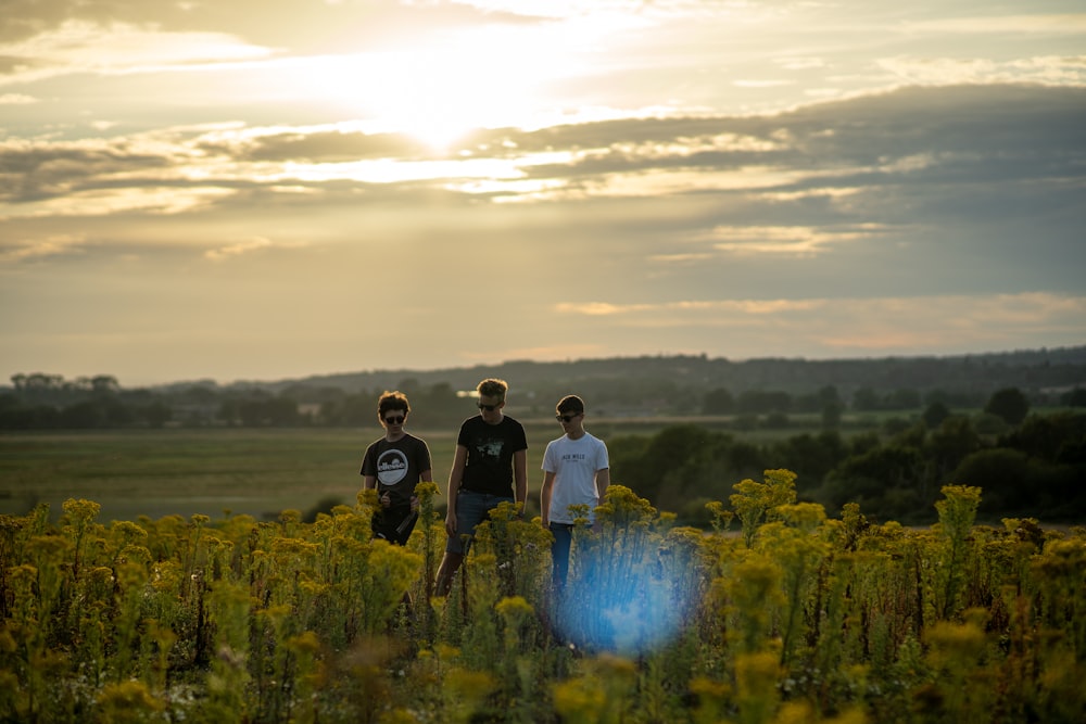 3 men standing on green grass field during daytime