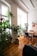 A cozy, sunlit Airbnb living room with warm wood accents and green plants.