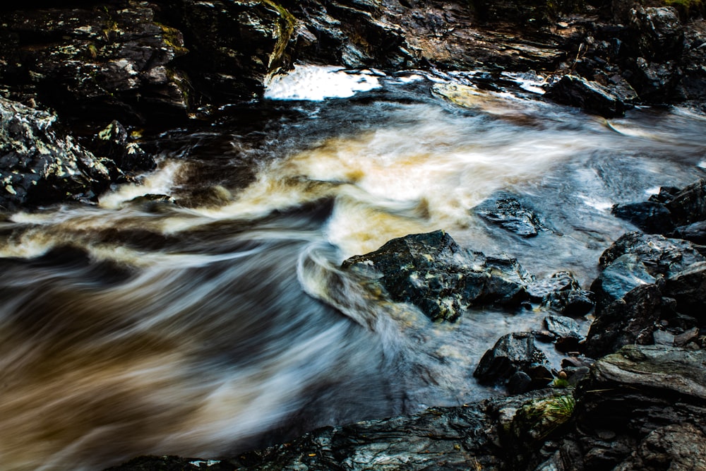 water falls on rocky mountain during daytime