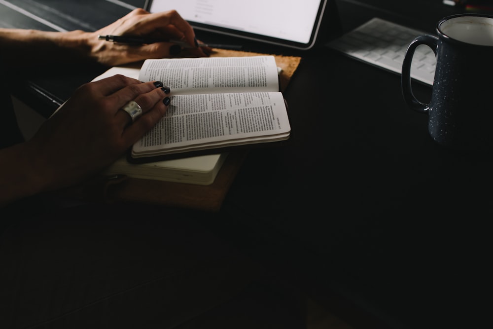 person reading book on table