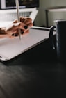 person writing on white paper on black table