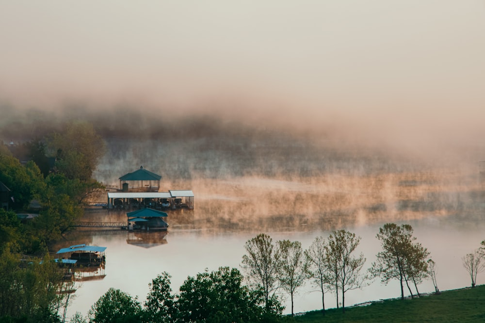 brown wooden house near green trees and lake during daytime