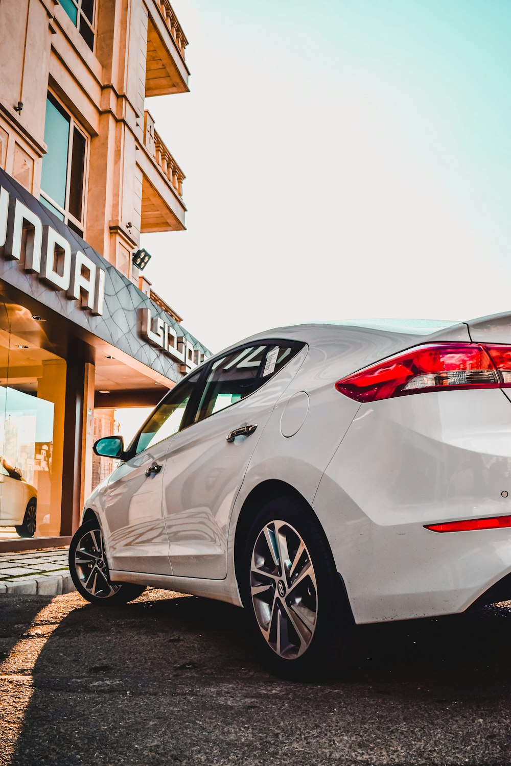 Sedán blanco estacionado en la acera durante el día