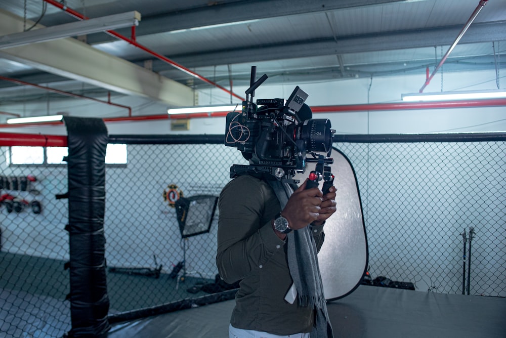a man holding a camera in front of a cage