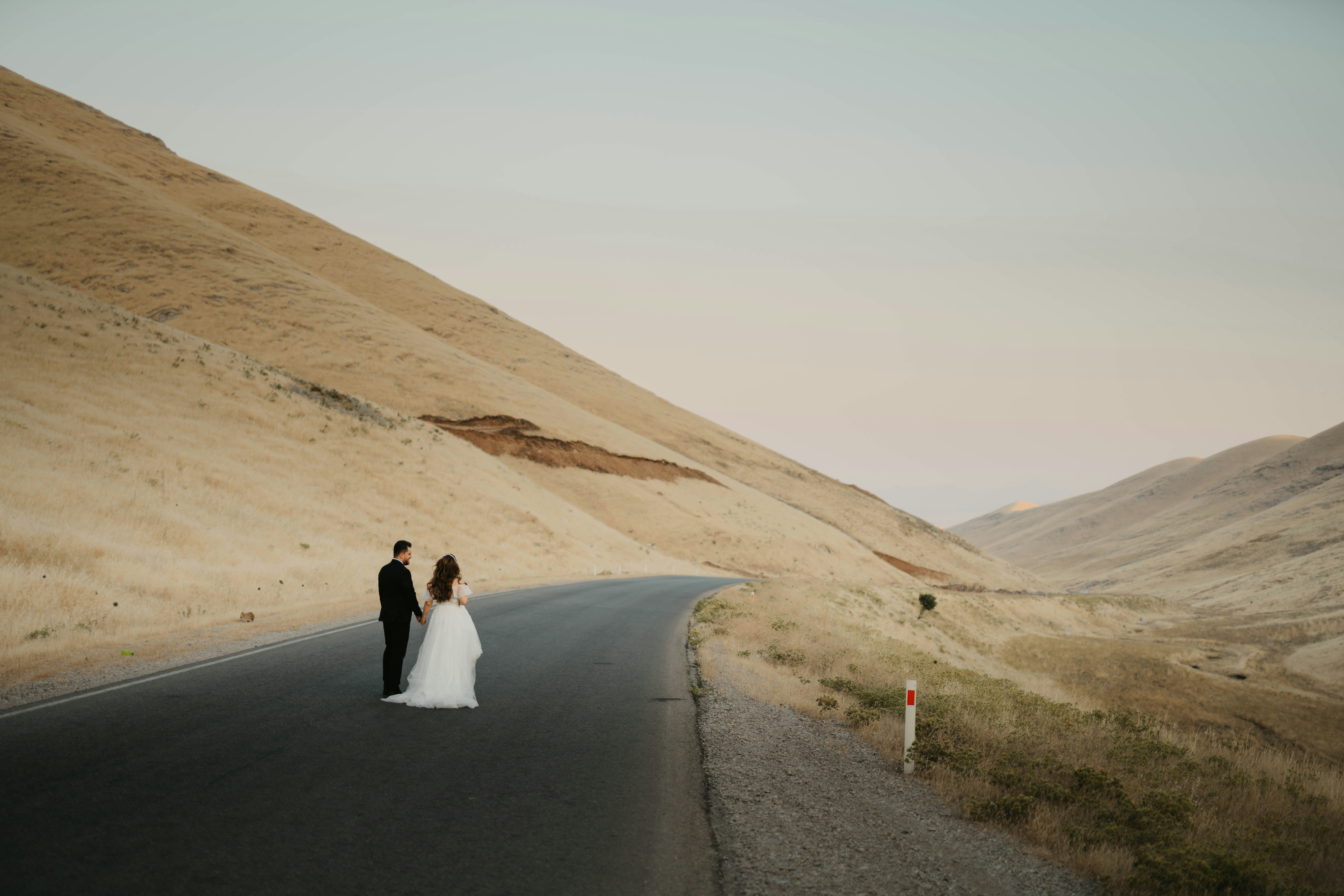 couple walking on gray asphalt road during daytime, 