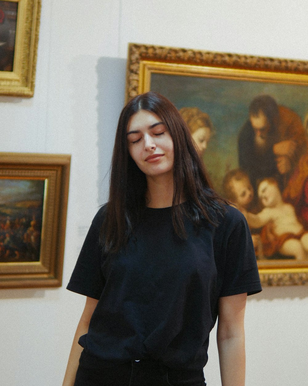 Femme en T-shirt à col rond noir debout près de la peinture