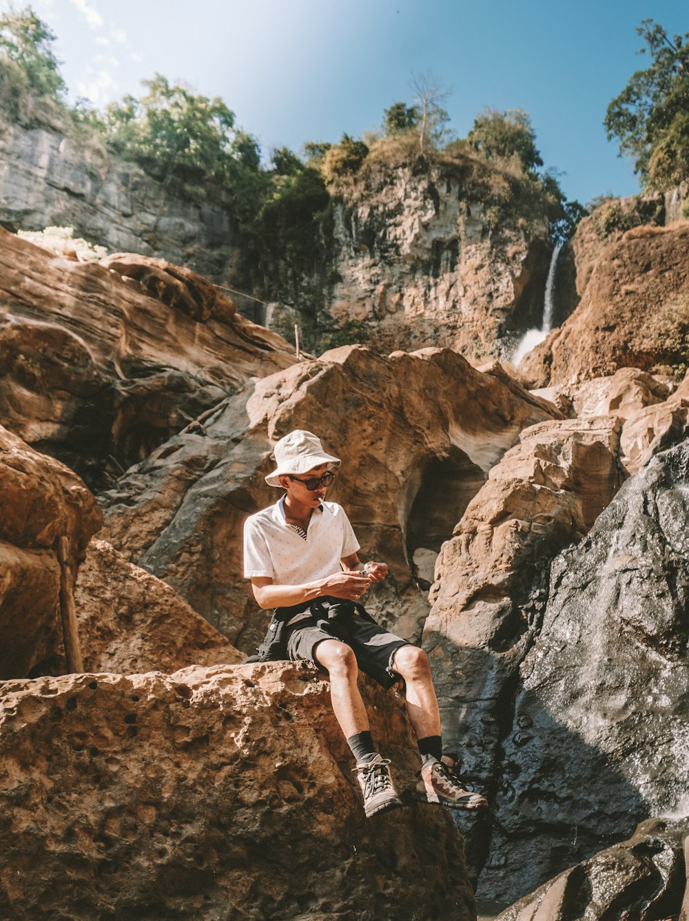 man in white t-shirt and black shorts riding bicycle on rocky mountain during daytime