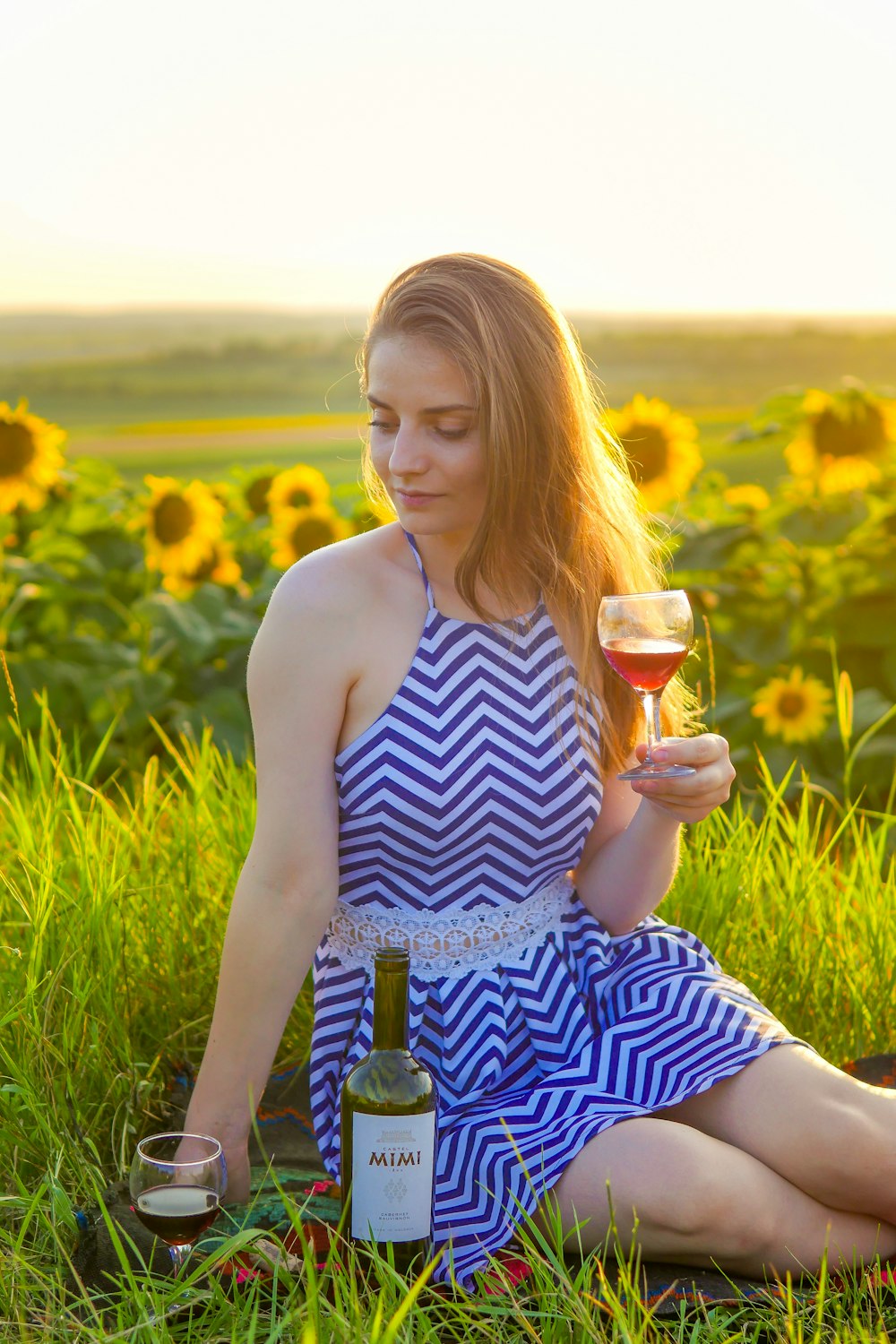 woman in blue and white stripe tank top holding wine glass