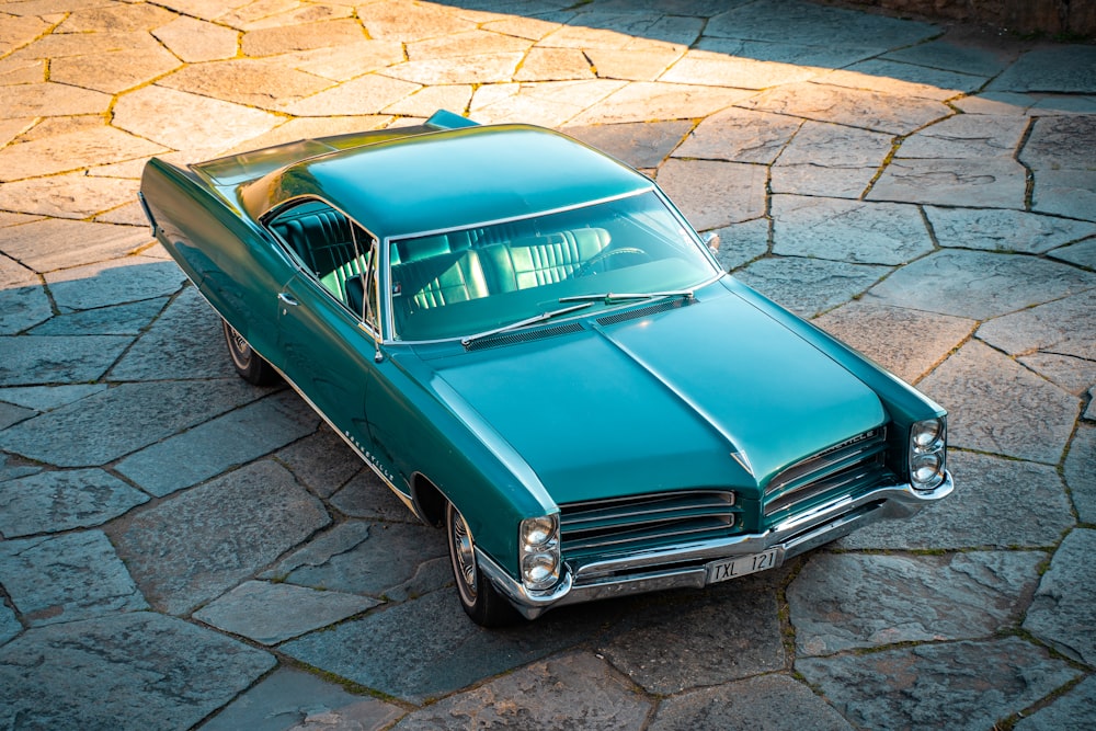 blue classic car parked on gray concrete pavement