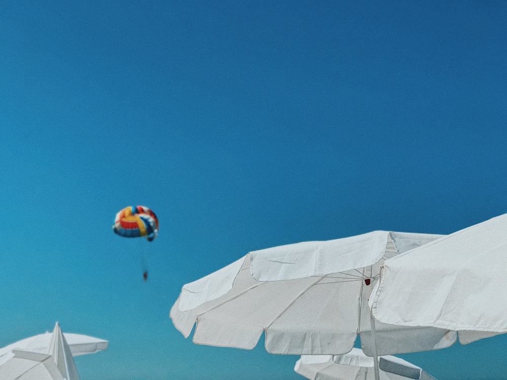 people riding on parachute under blue sky during daytime