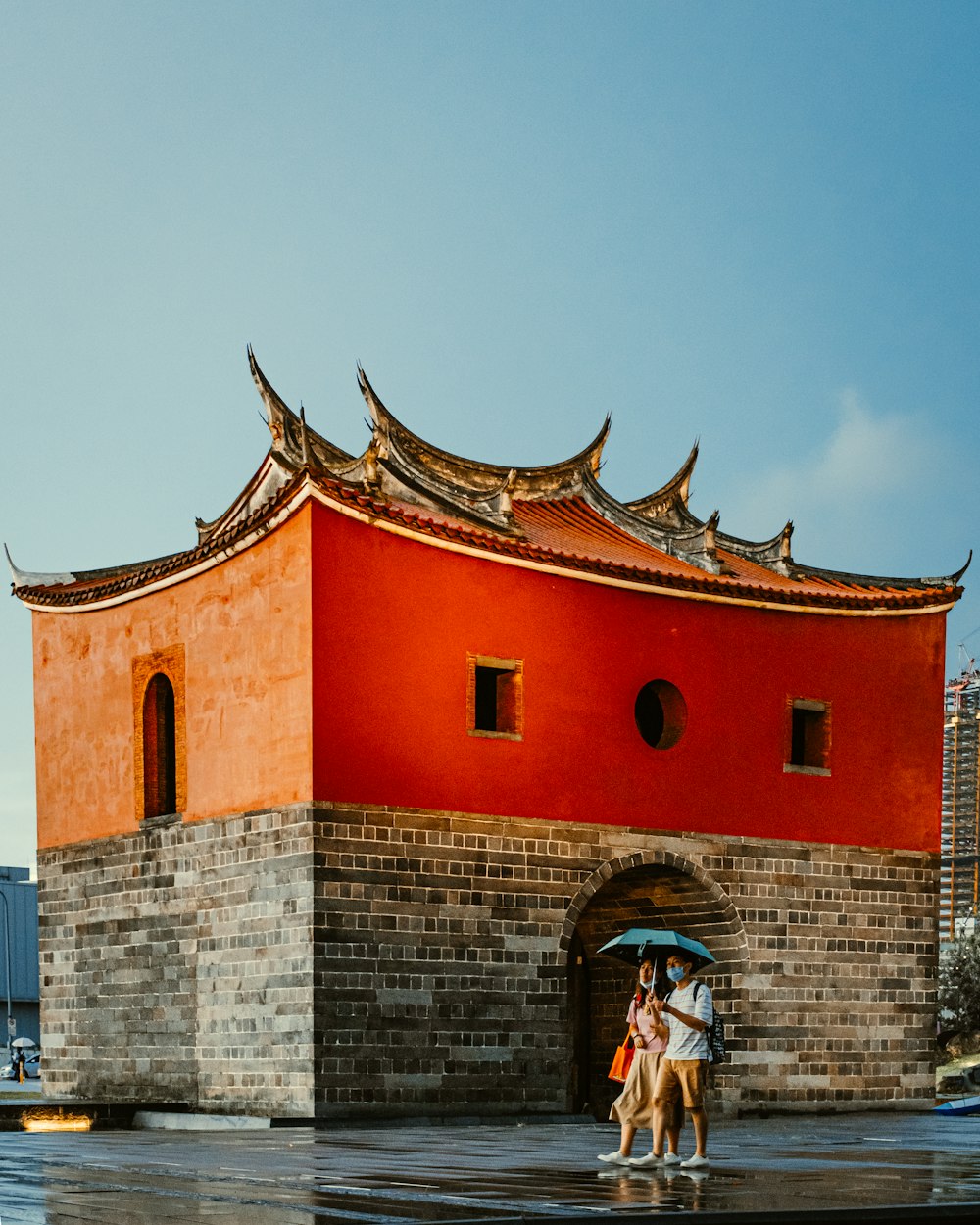 man in black jacket standing beside red concrete building during daytime