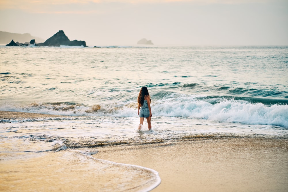 woman in black dress walking on beach during daytime