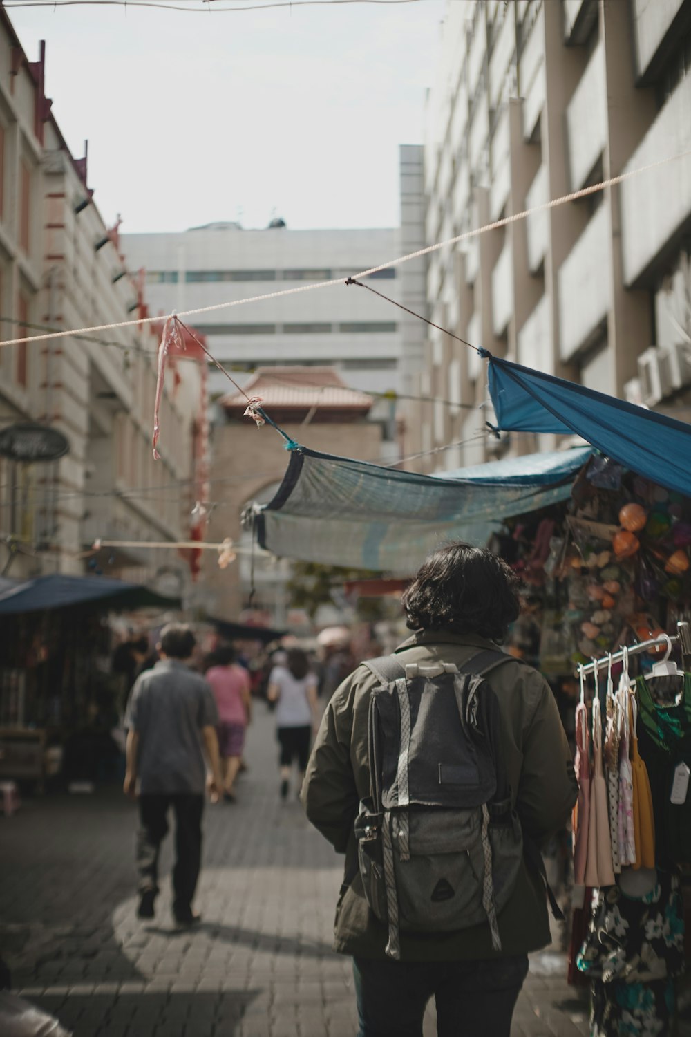 man in gray jacket standing near blue and white umbrella during daytime