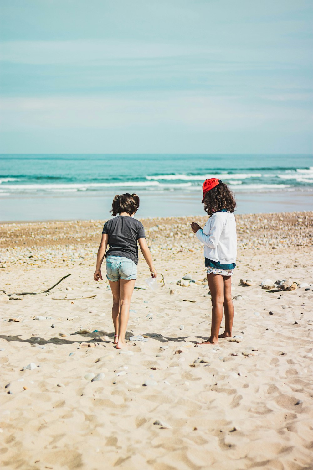 2 women walking on beach during daytime