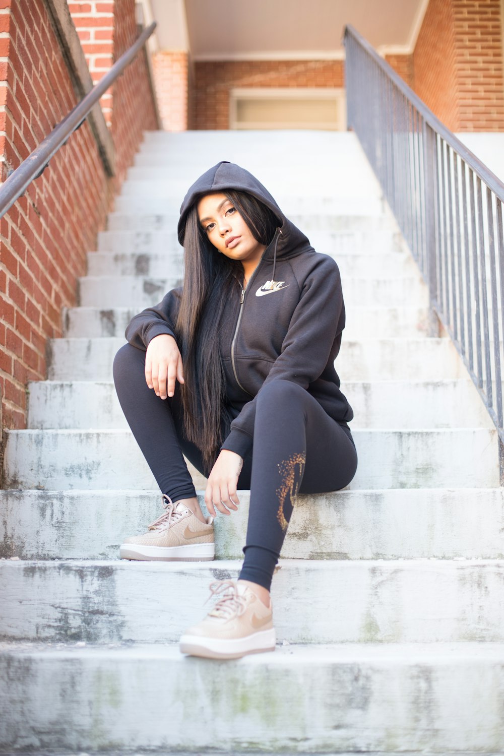 woman in black hoodie and black pants sitting on concrete stairs