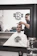 A happy young man with a fresh fade haircut sitting in the barber chair inside an industrial-style barbershop.