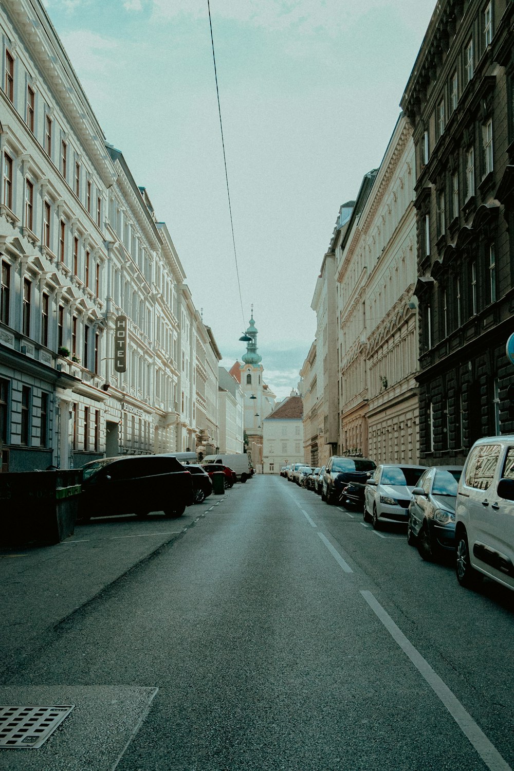 cars parked on side of the road in between buildings during daytime