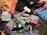 A collection of various athletic apparel and accessories laid out, including sports bras, tops, headbands, and tags. The items are in different colors and patterns, such as pastel pink, blue, and floral designs. A black jacket and several pieces still have brand tags attached.