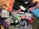 A collection of various athletic apparel and accessories laid out, including sports bras, tops, headbands, and tags. The items are in different colors and patterns, such as pastel pink, blue, and floral designs. A black jacket and several pieces still have brand tags attached.