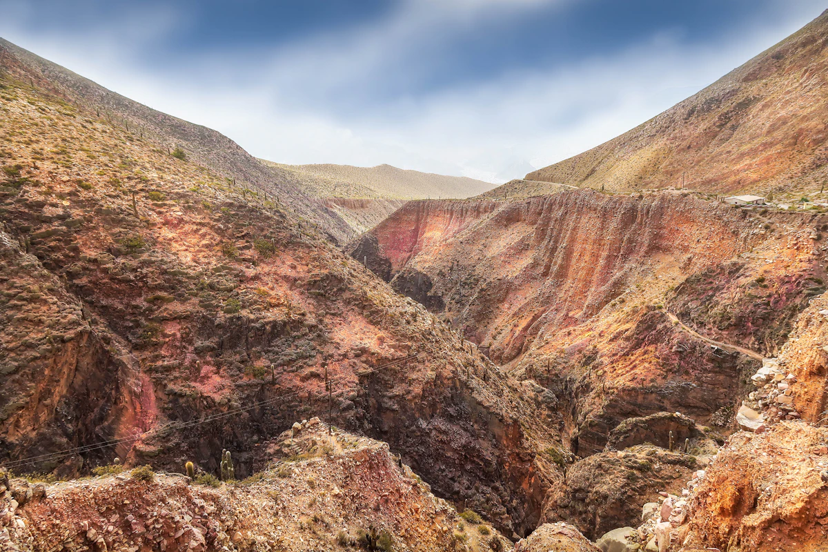 A red rock ravine cutting through the hills near Tilcara under a pale sky
