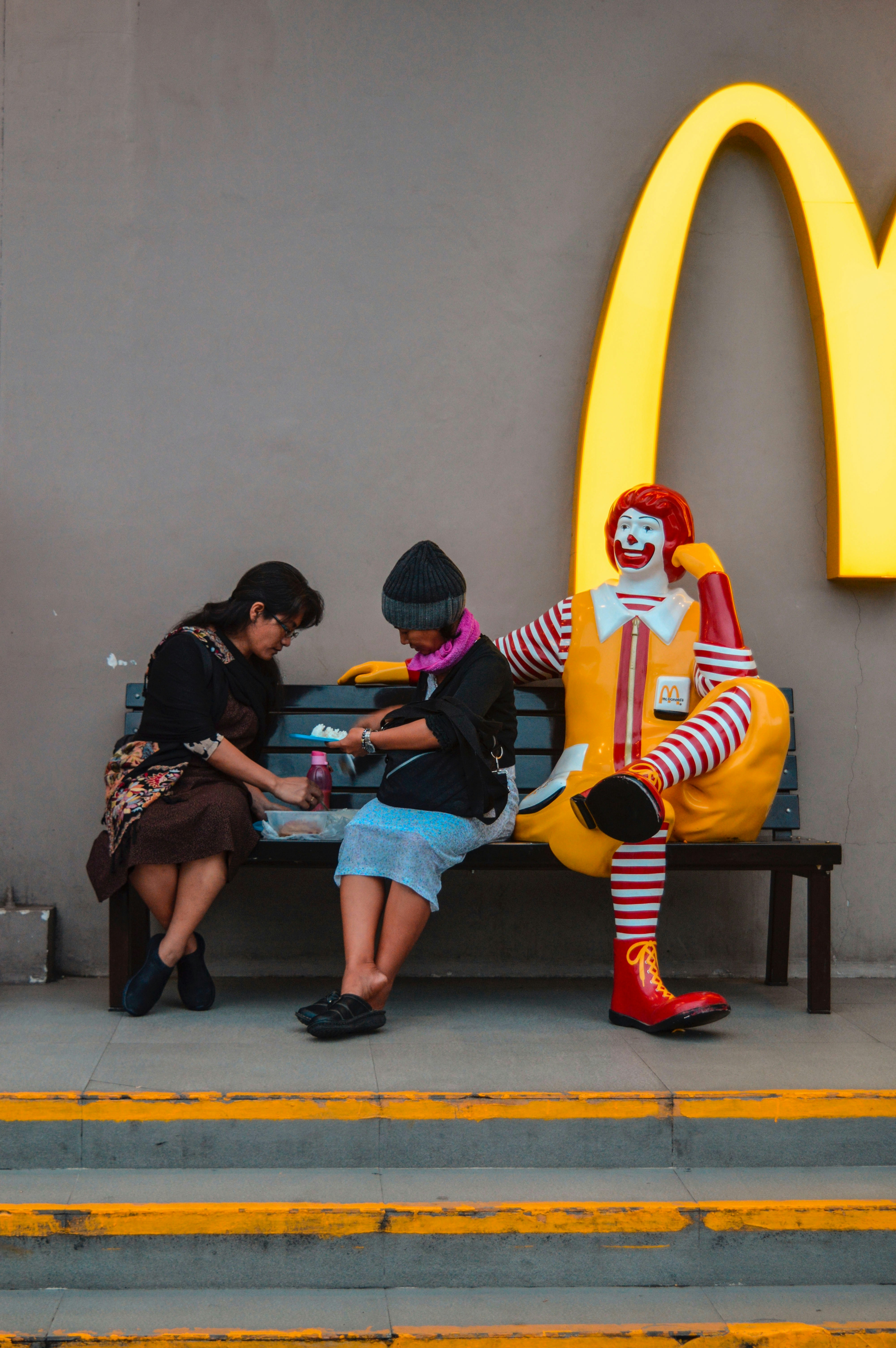 woman in black jacket sitting on yellow and red chair of McDonald's