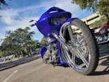 Vibrant metallic blue motorcycle wrap shining under sunlight on a city street.