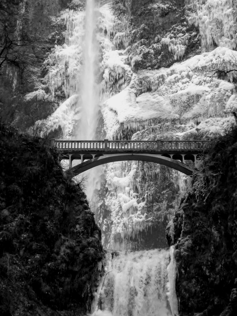 gray scale photo of bridge near waterfalls