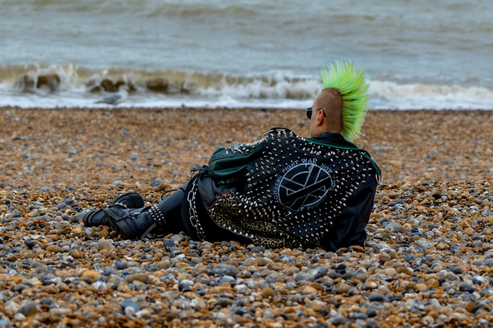 femme en bottes de cuir noir assise sur le rivage de la plage pendant la journée