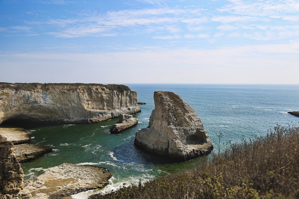 brown rock formation on sea under blue sky during daytime