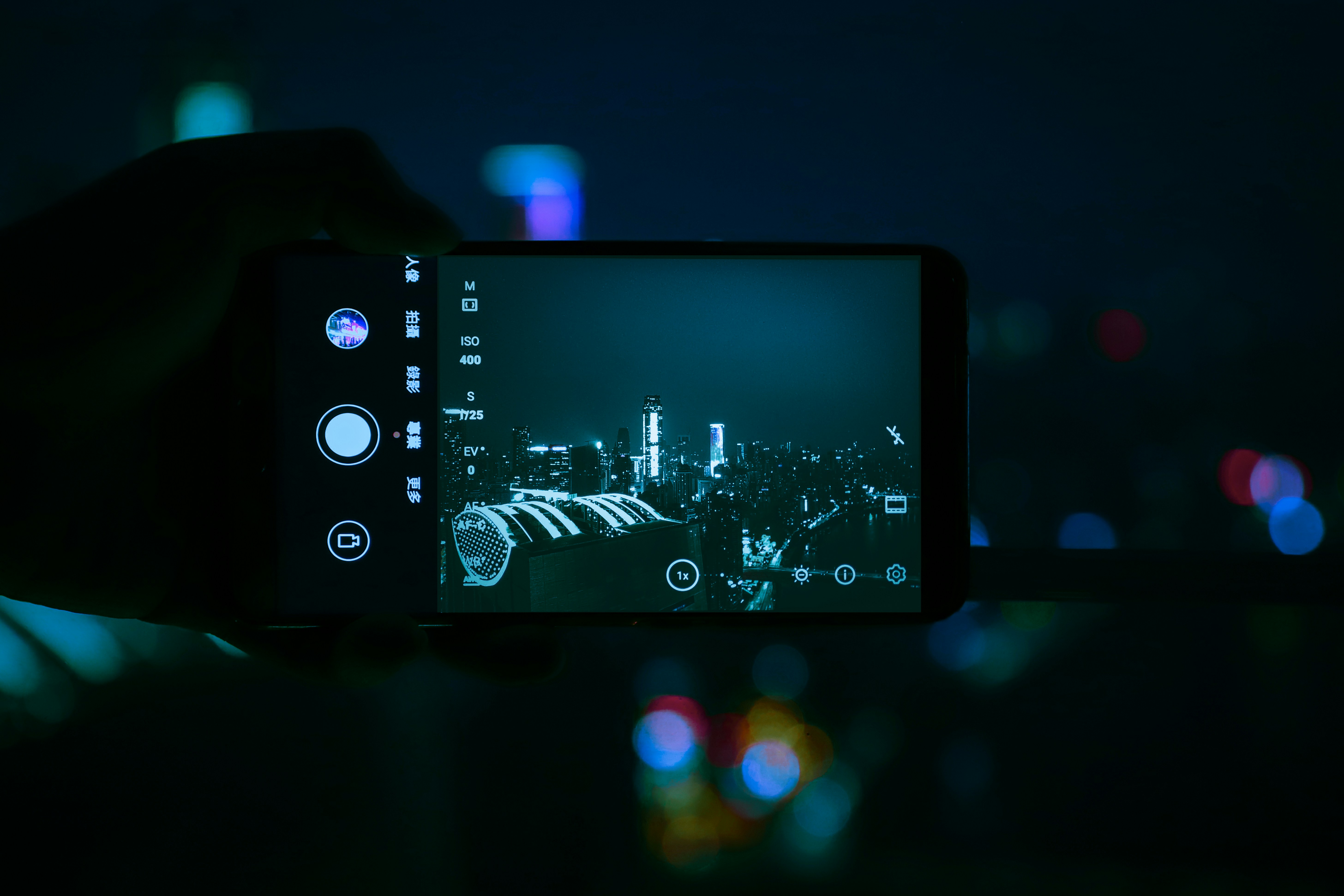 Smartfon w dłoni na tle rozświetlonego miasta