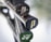 Close-up of the handles of three tennis rackets leaning together, with visible brand markings. The handles are black with textured grips, and each end cap has a unique design or logo, one being green and another featuring the word 'AIR'. The background is out of focus, highlighting the rackets.
