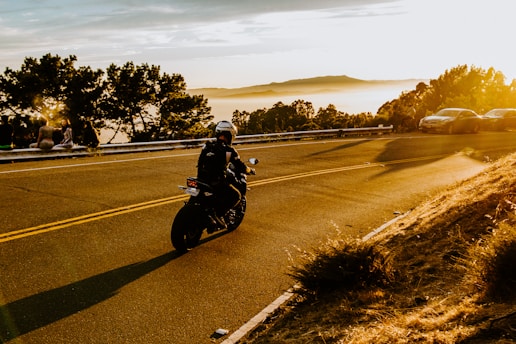 Motorcycle speeding on a winding road at sunset.