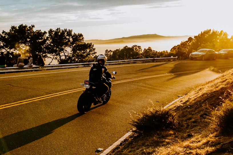 A group of motorcyclists riding together on a scenic country road at sunset.