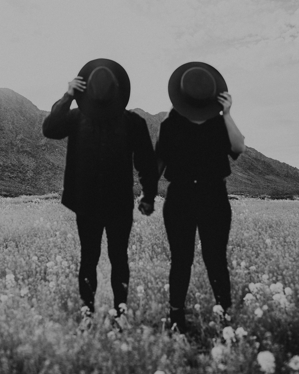 grayscale photo of 2 person standing on flower field