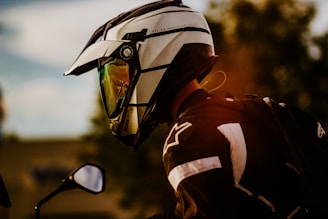 a man wearing a helmet and sunglasses standing next to a motorcycle