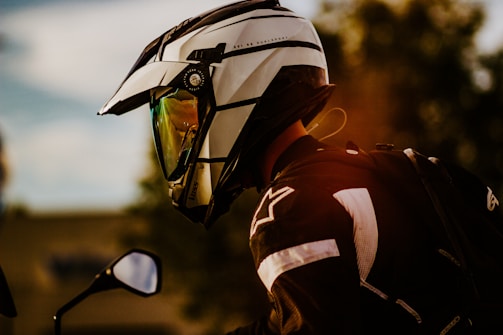 a man wearing a helmet and sunglasses standing next to a motorcycle
