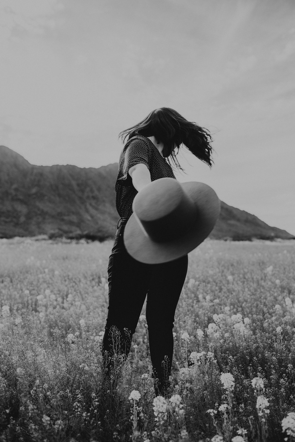 a woman standing in a field with a hat