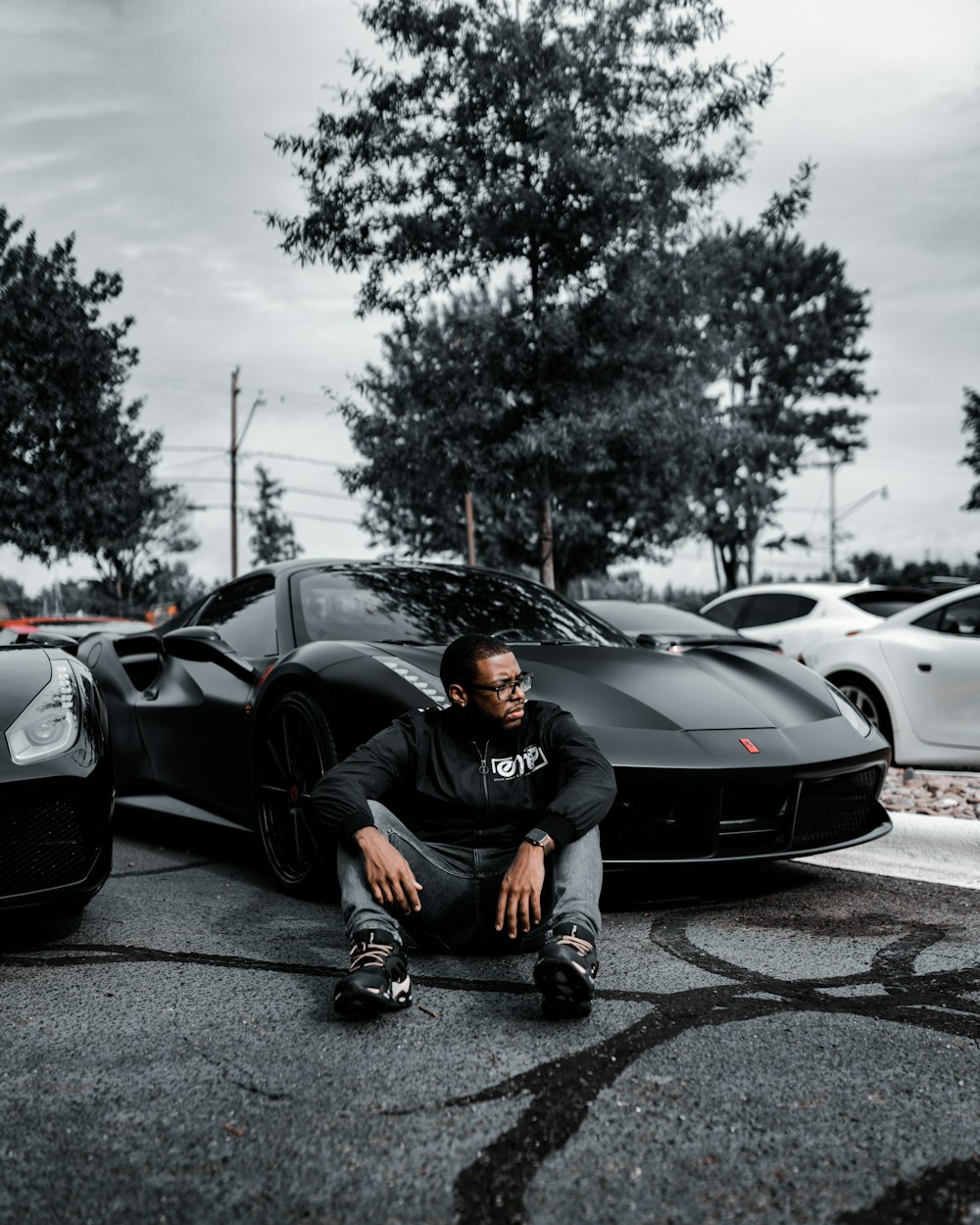 a man sitting in front of a black sports car