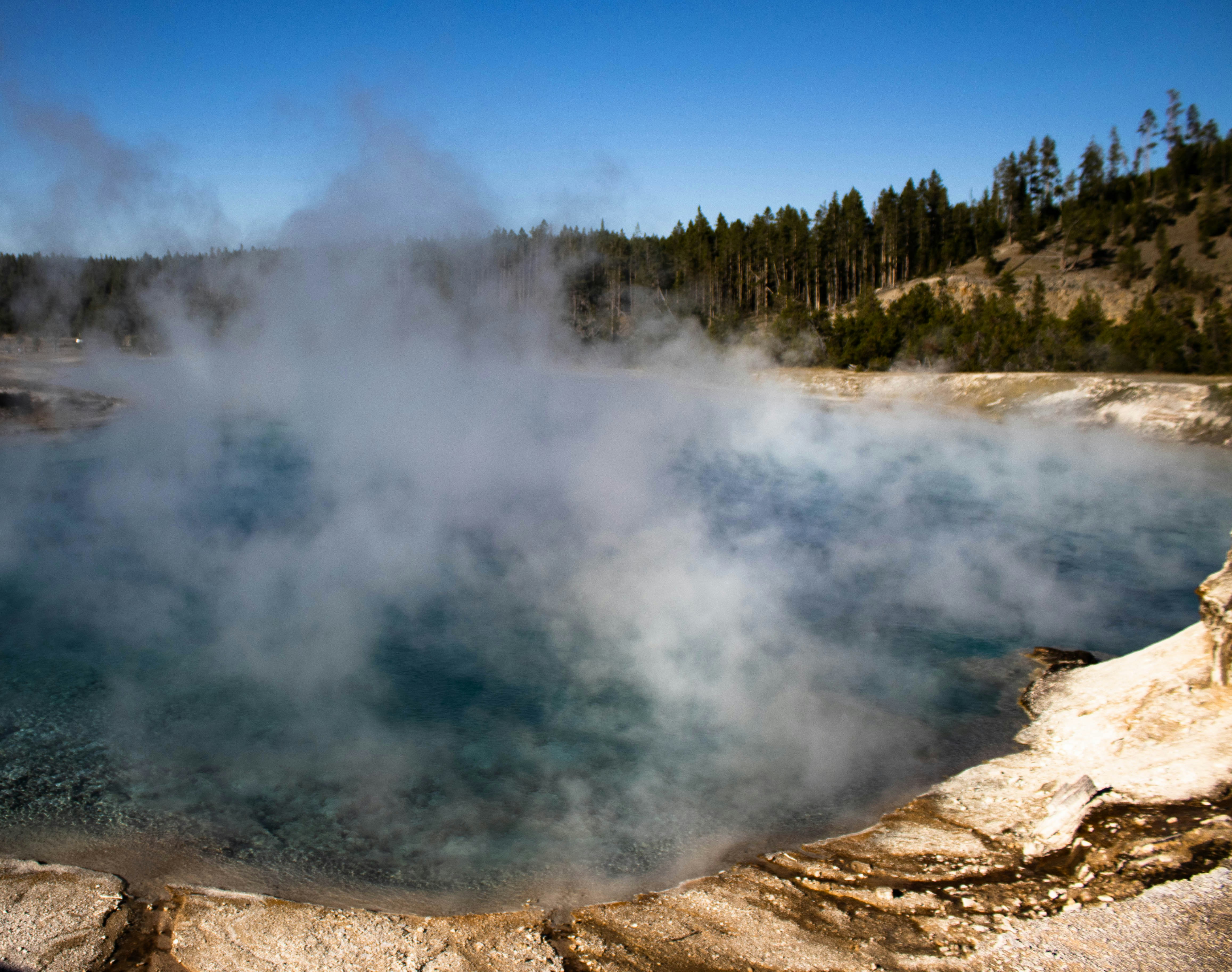 AuroraSpa geothermal pools at night with aurora borealis overhead, deep teal water glowing, volcanic rock edges, dramatic night sky