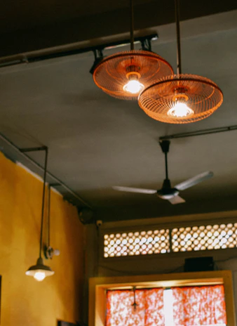 Close-up of hands wiring a ceiling fan with neat, professional work in a cozy living room.