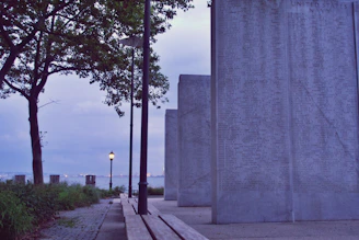 A serene outdoor scene showing a metal plaque with a QR code attached to a memorial stone, bathed in gentle sunlight.