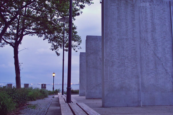 A serene outdoor scene showing a metal plaque with a QR code attached to a memorial stone, bathed in gentle sunlight.