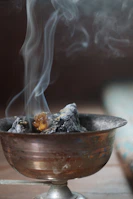 Smoke curling up from burning sarghine incense in a rustic Moroccan setting.