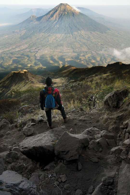 man in blue jacket and black pants standing on rock mountain during daytime in Wonosobo Indonesia