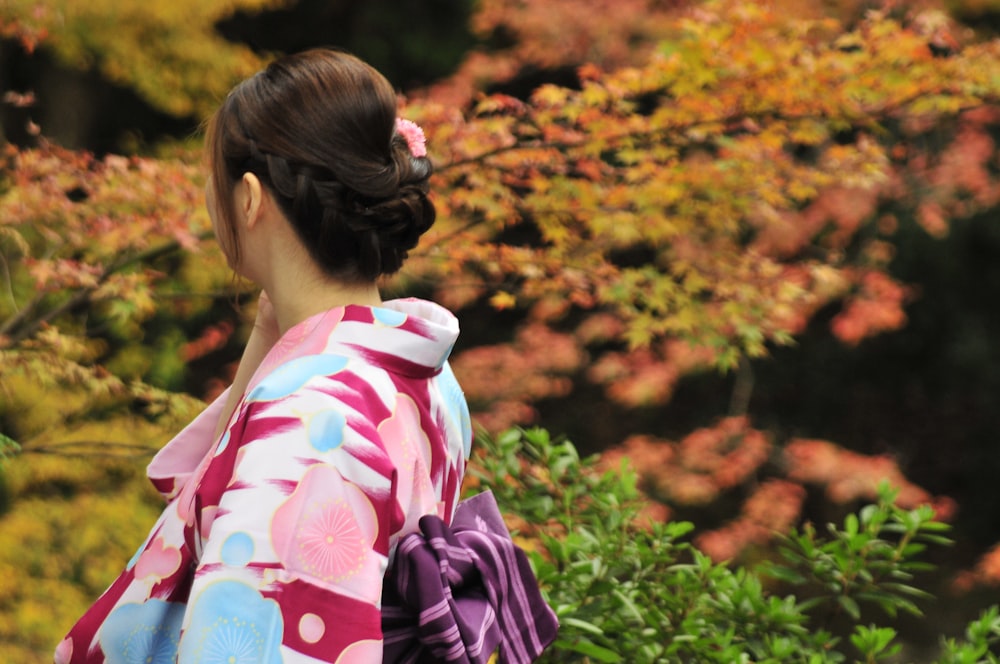 woman in white pink and blue floral kimono standing on green grass field during daytime