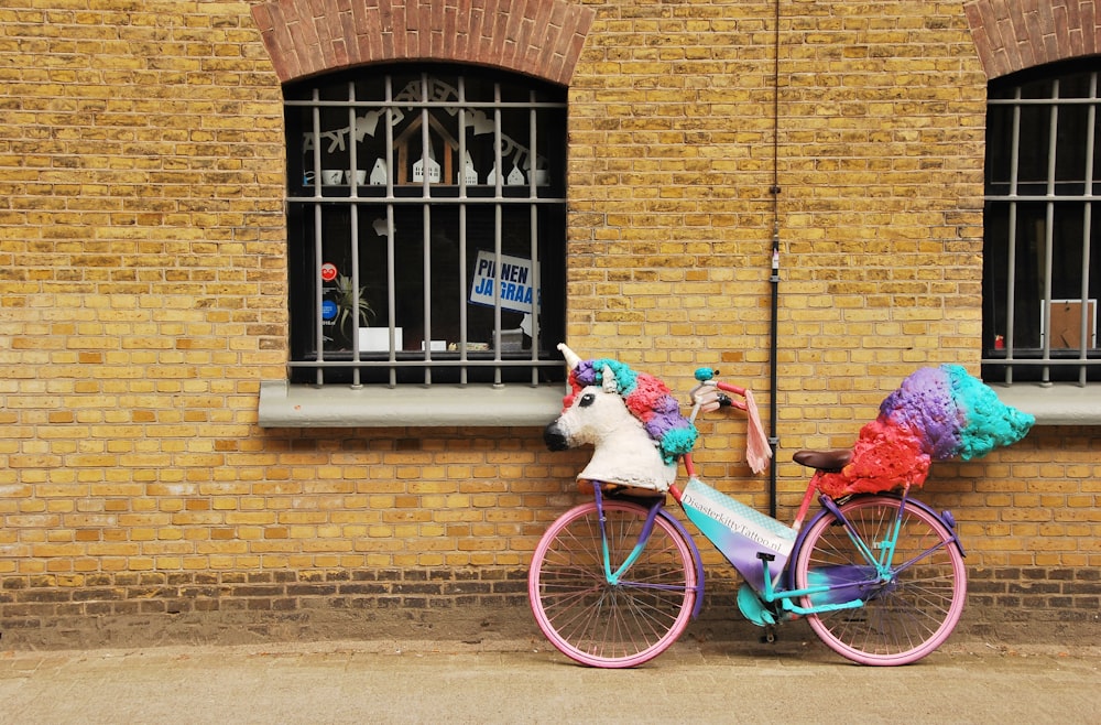 a pink and blue bike with two stuffed animals on it