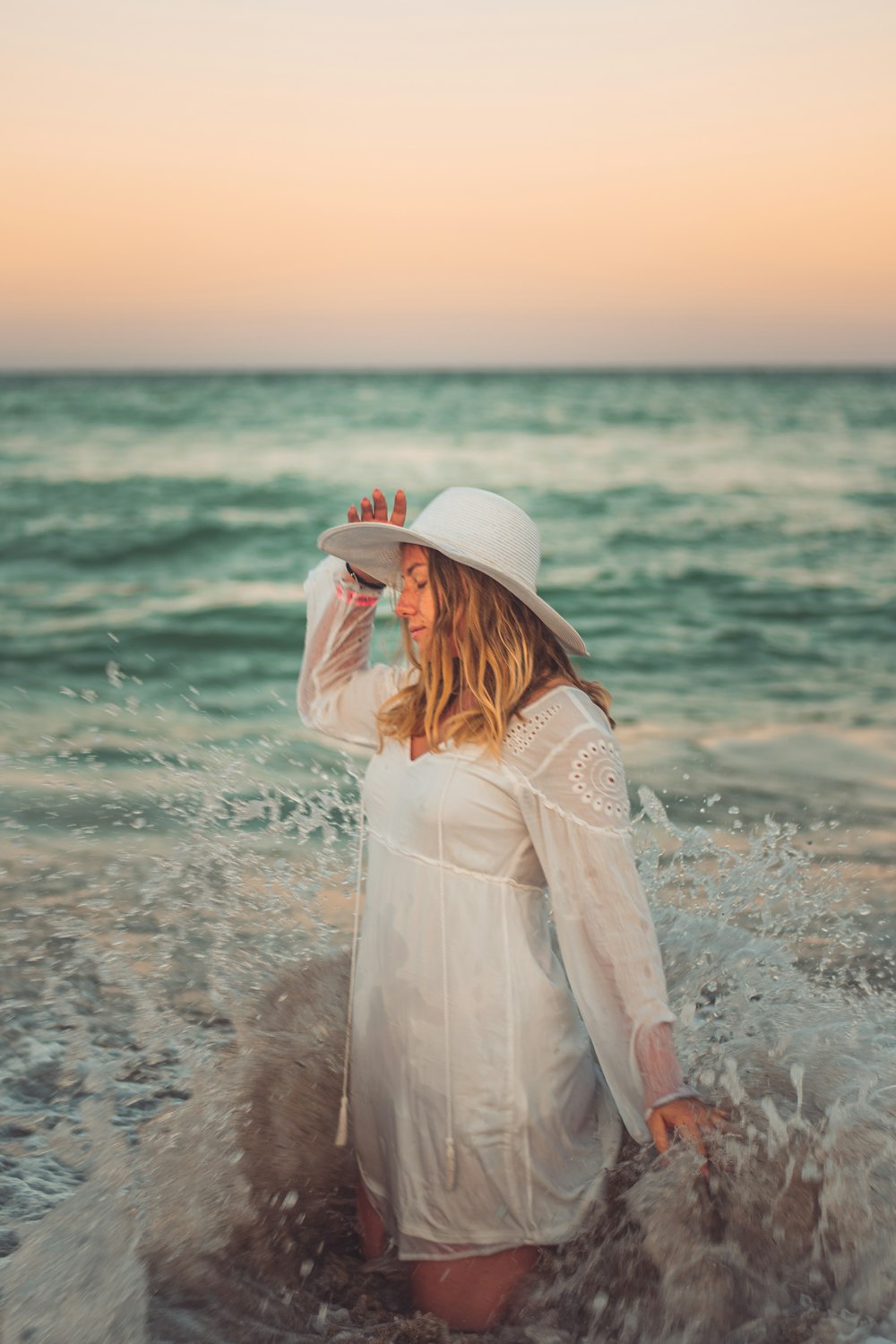 woman in white long sleeve dress standing on beach during daytime