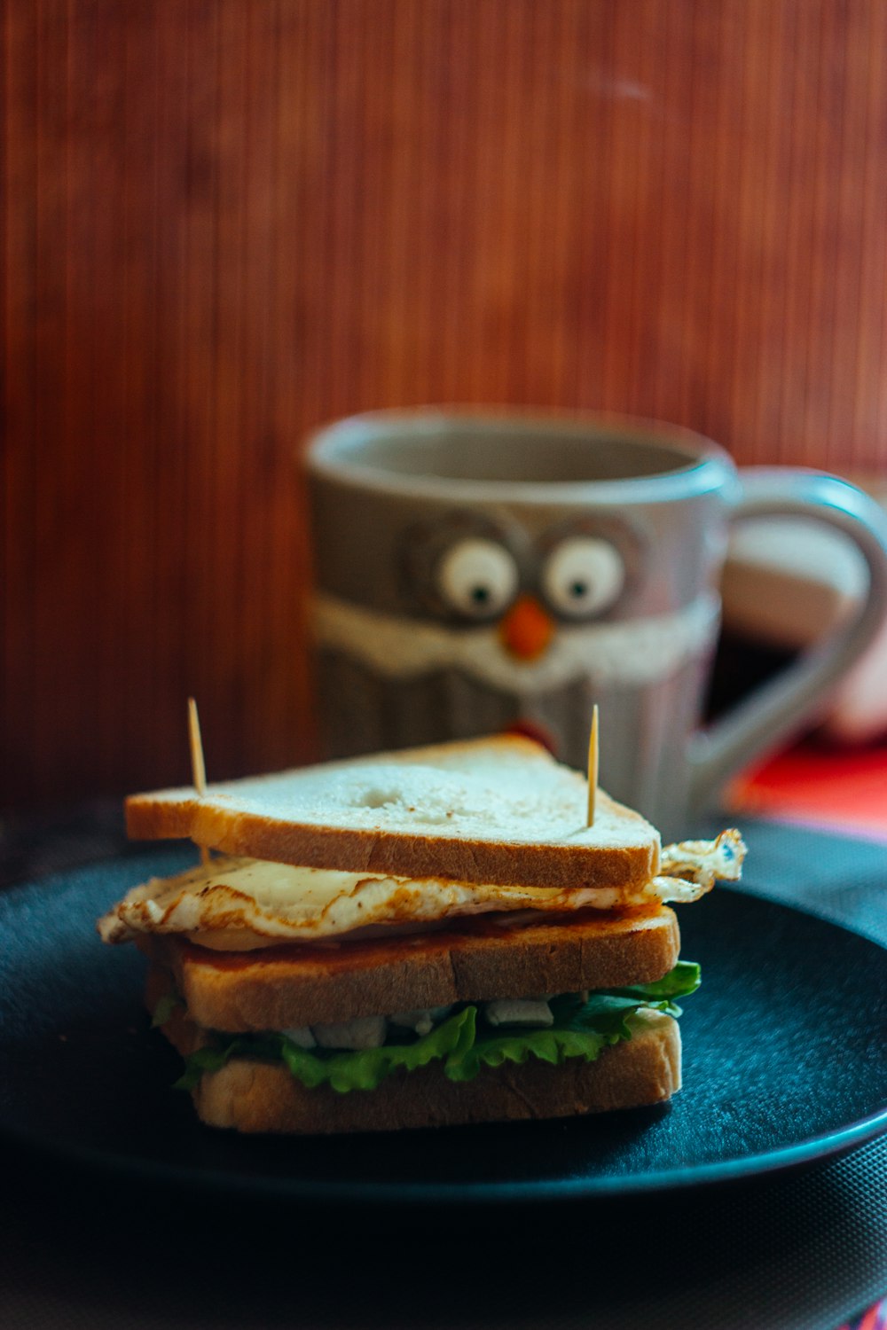 sandwich on blue ceramic plate beside white and black ceramic mug