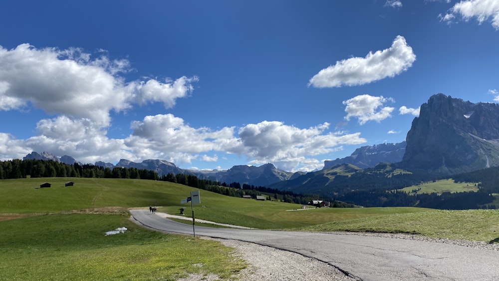 green grass field under blue sky and white clouds during daytime